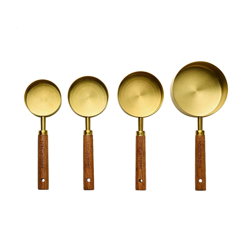 Four brass measuring spoons with wooden handles on a white background